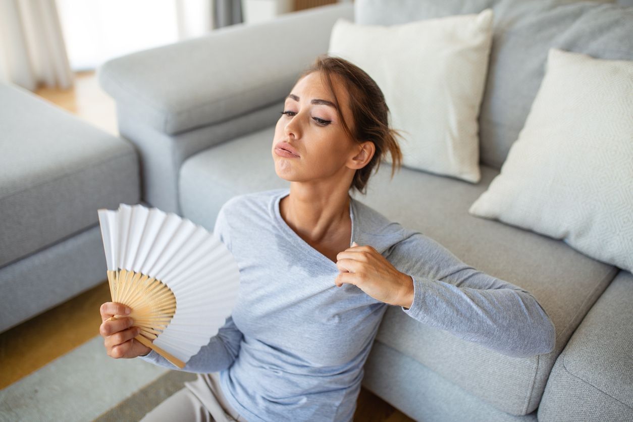 Woman cooling herself with a fan during hot weather at Rewind Time event in Missouri and Kansas.