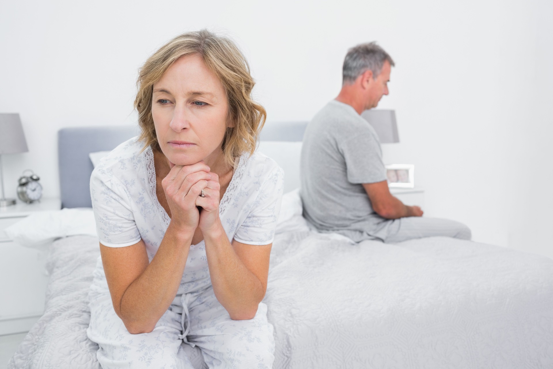 Unhappy couple sitting on different sides of bed